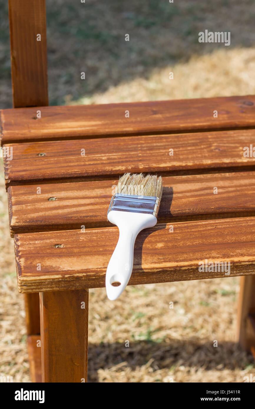 brush laying on wooden boards of a chair to painting wood preservative paint Stock Photo