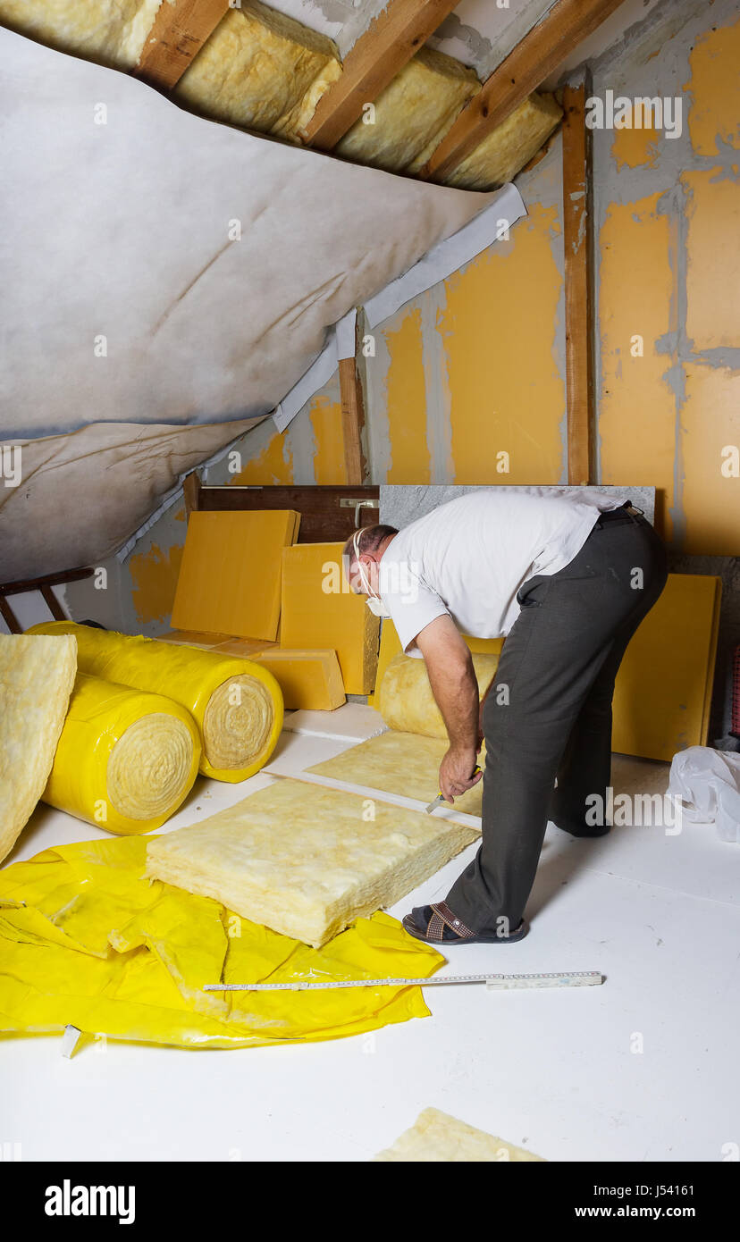 handyman cutting the termal insulation at the attic Stock Photo