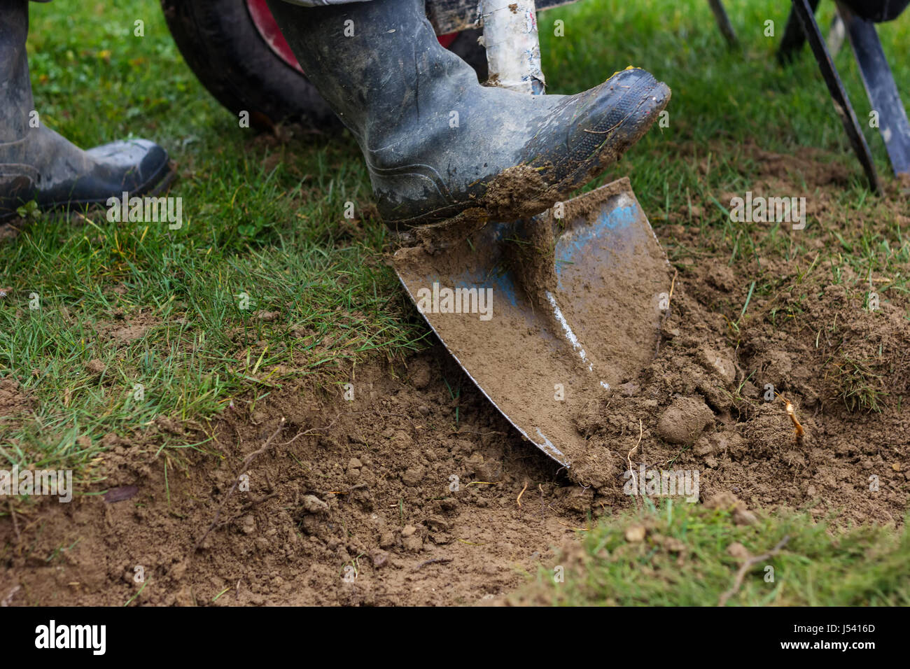rubber boots with shovel digging out Stock Photo