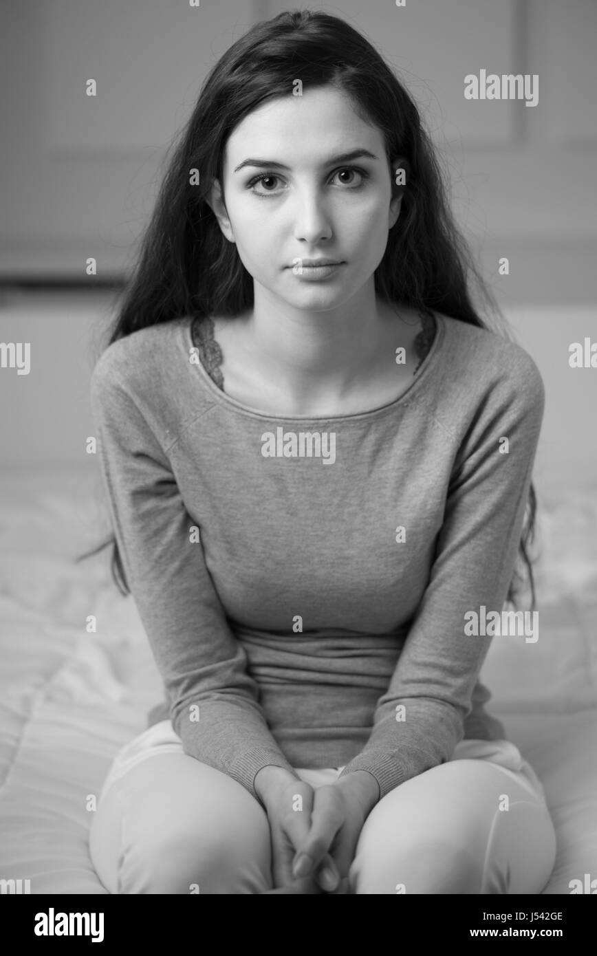 Young woman sitting on the bed at home and looking at camera Stock ...