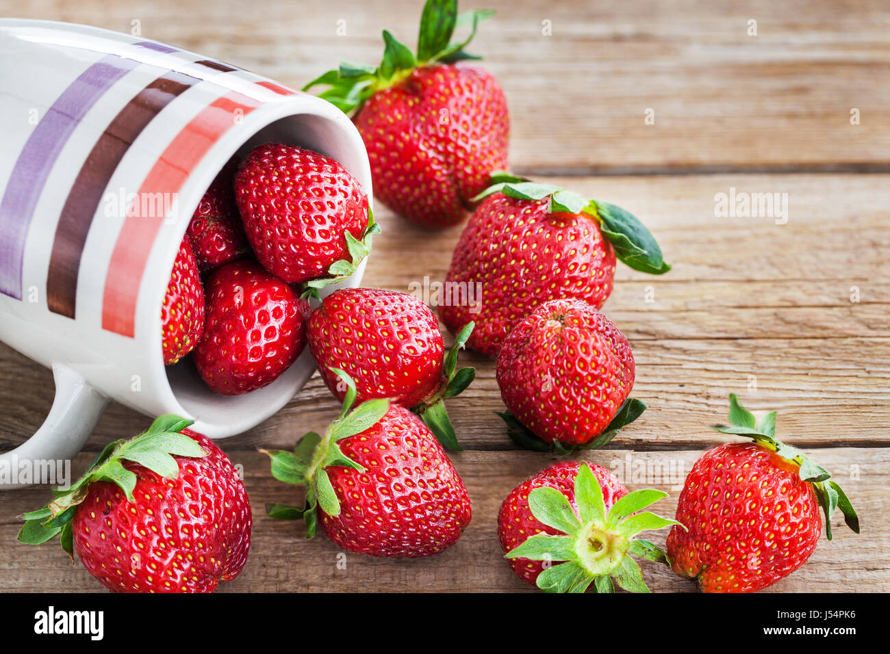 Fresh ripe strawberries in mug, wooden background Stock Photo - Alamy