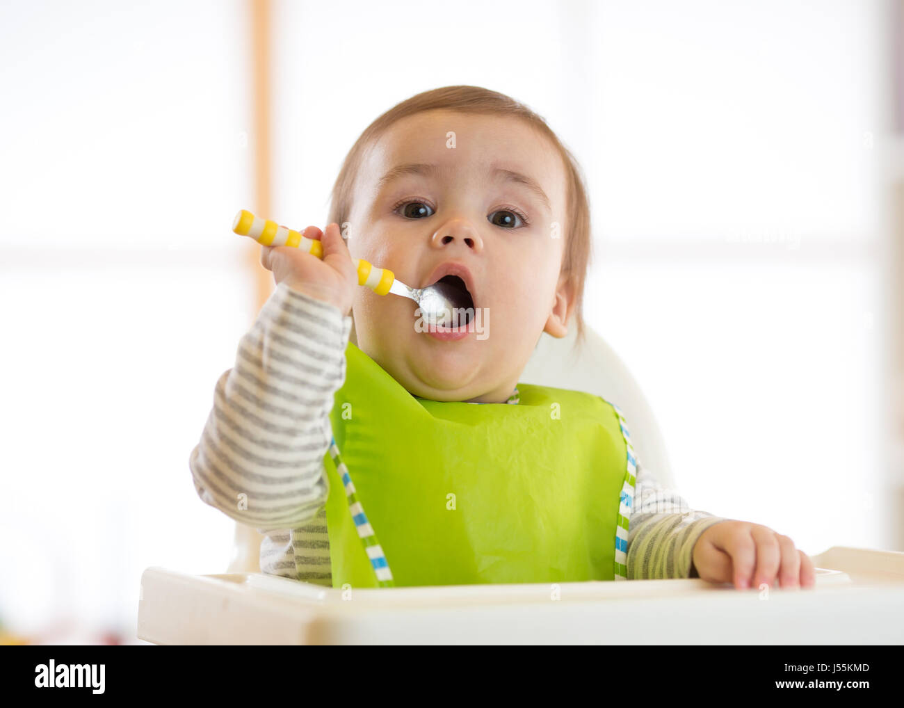 Happy baby boy spoon eats itself Stock Photo