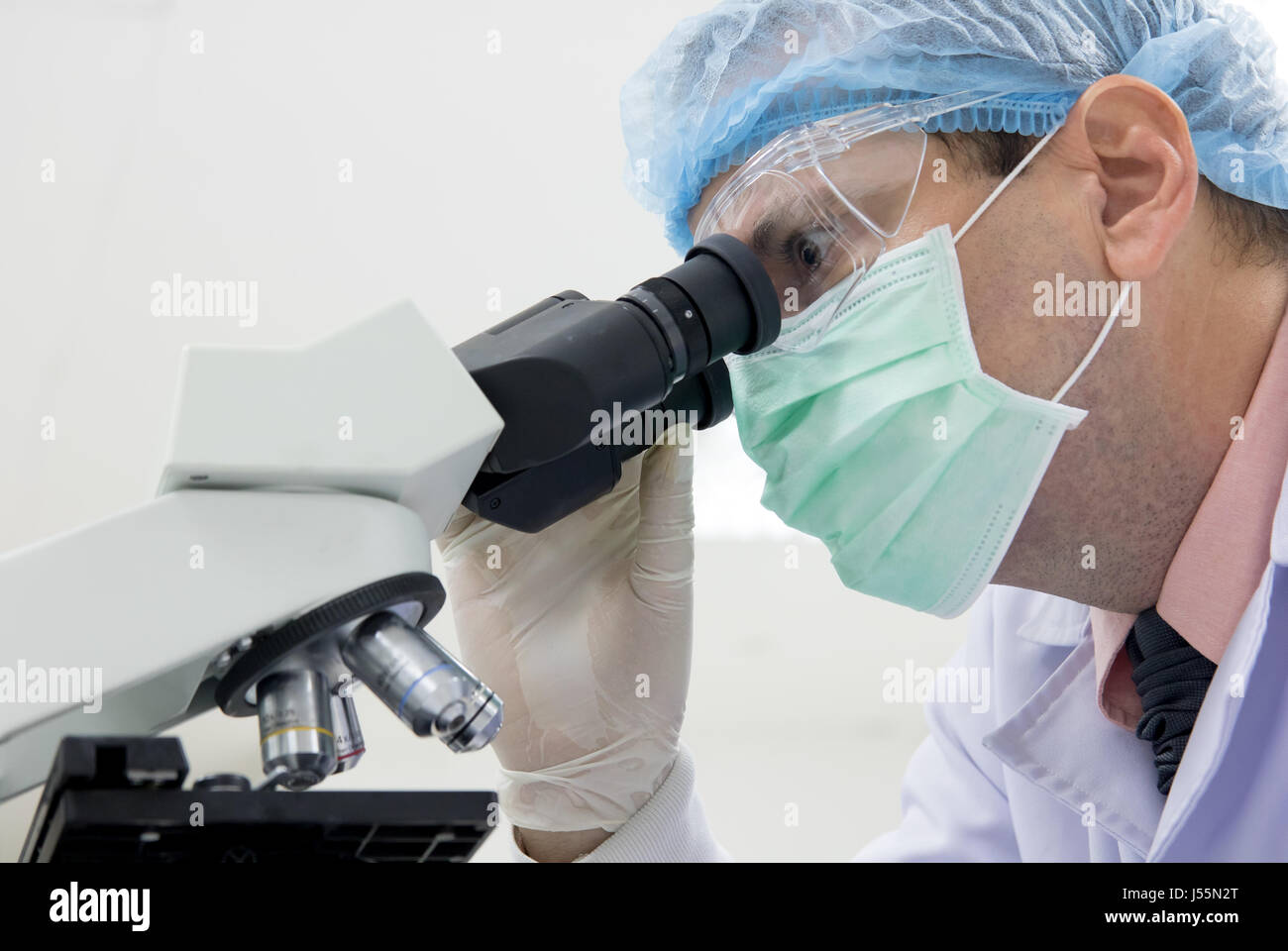A portrait of a scientist examining organic life under a microscope