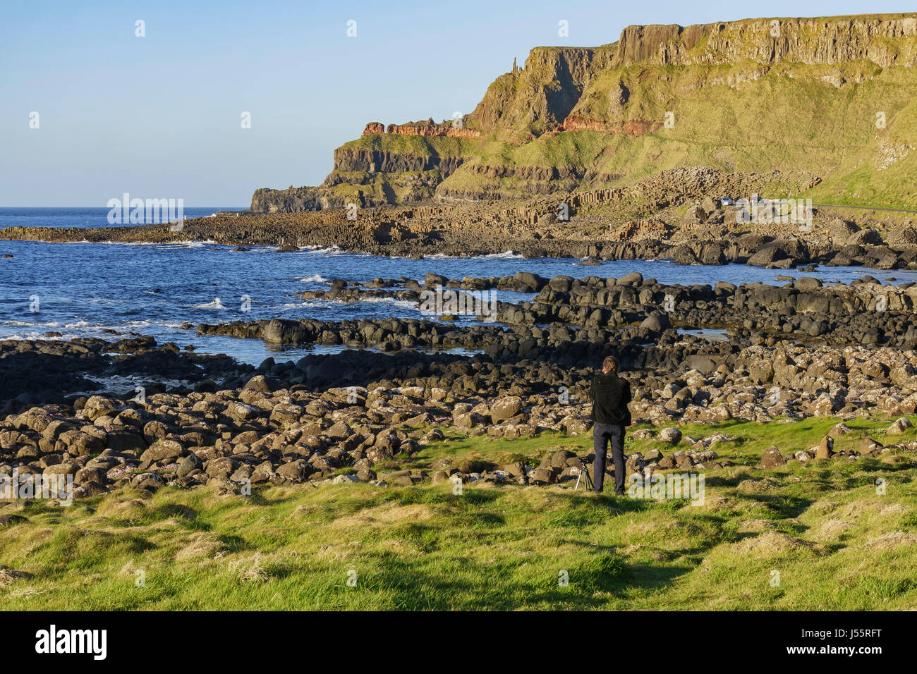 Photographer taking picture of the famous ancient volcanic eruption - Giant's Causeway of County Antrim, Northern Ireland Stock Photo