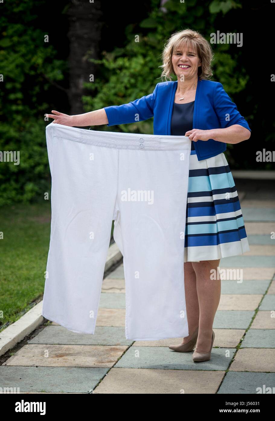 Tracey Topping, 47, from Northampton, holds her old trousers during a photo call at the Roof Gardens in Kensington, London, after being announced as Slimming World's Greatest Loser 2017 following a weight loss of 18 stone and dropping from a 34/36 to 10/12 dress size. Stock Photo