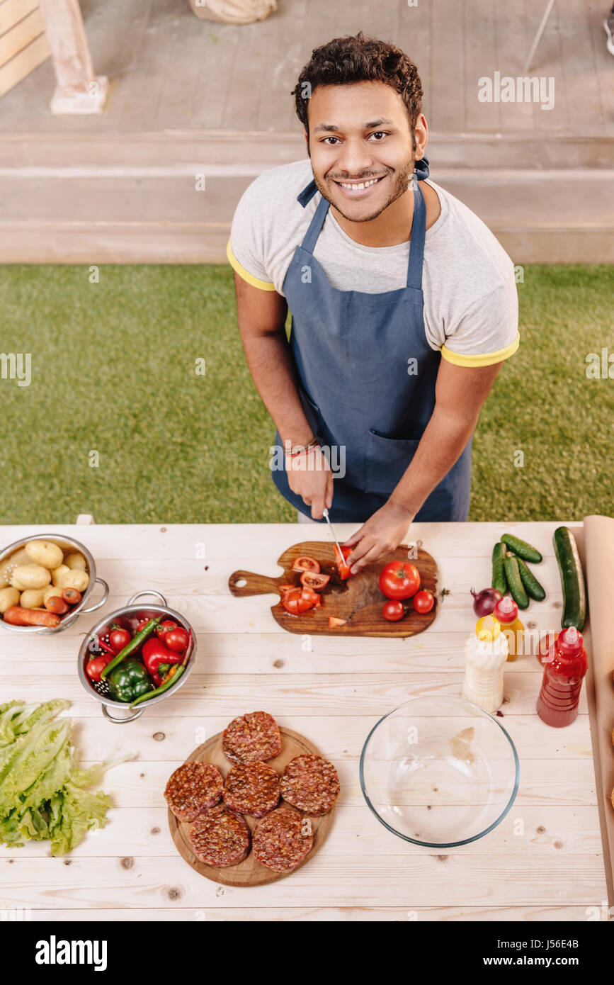 man making burgers and cutting red tomatoes outdoors Stock Photo Alamy