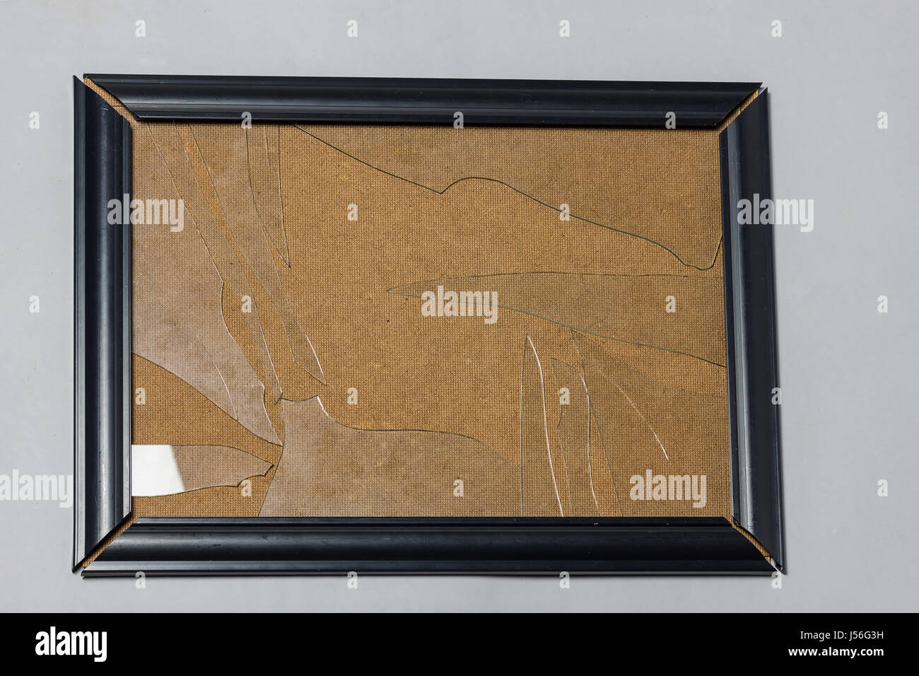black picture frame with broken glass plate in front of grey background