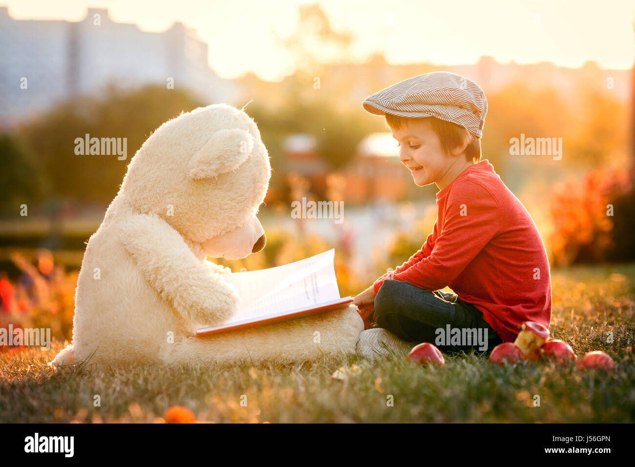 Adorable little boy with his teddy bear friend in the park on sunset ...