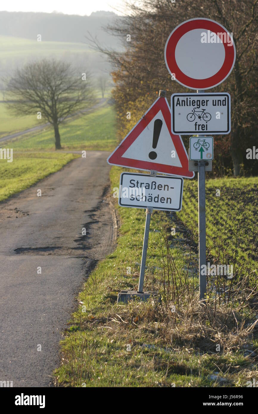 tree dirt road signposts attention cycle track traffic signs path way road Stock Photo