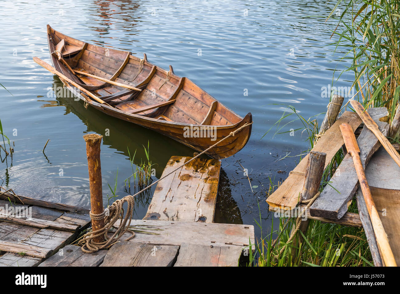 Wooden boat at the pier is tied to a wooden pole Stock Photo - Alamy