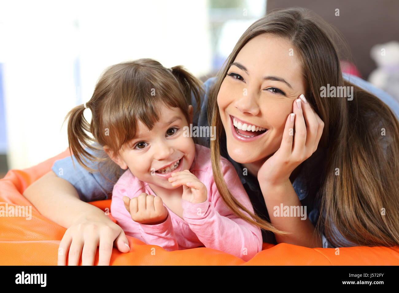 Front view portrait of a happy mother and daughter looking to camera in the living room at home Stock Photo
