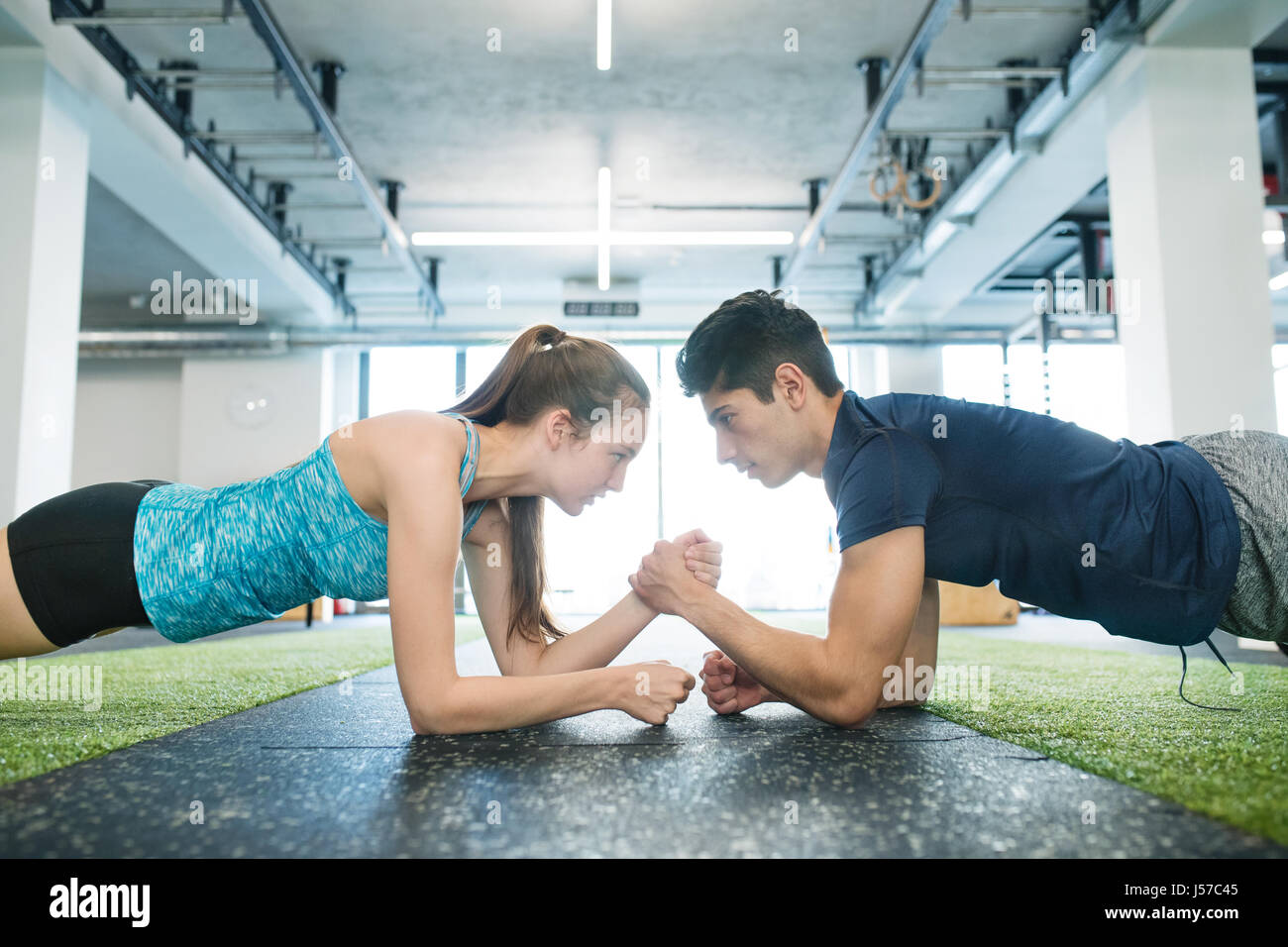 Young fit couple in gym in plank position exercising core muscle Stock Photo