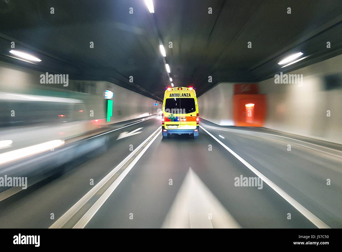 Ambulance speeding in road tunnel with traffic motion blur background Stock Photo
