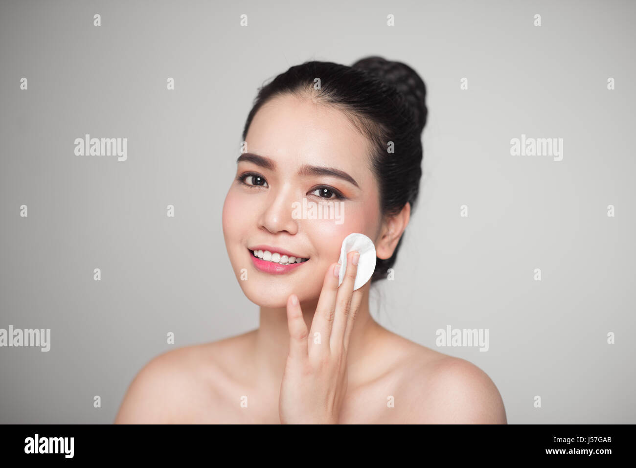 Happy smiling beautiful asian woman using cotton pad cleaning skin ...
