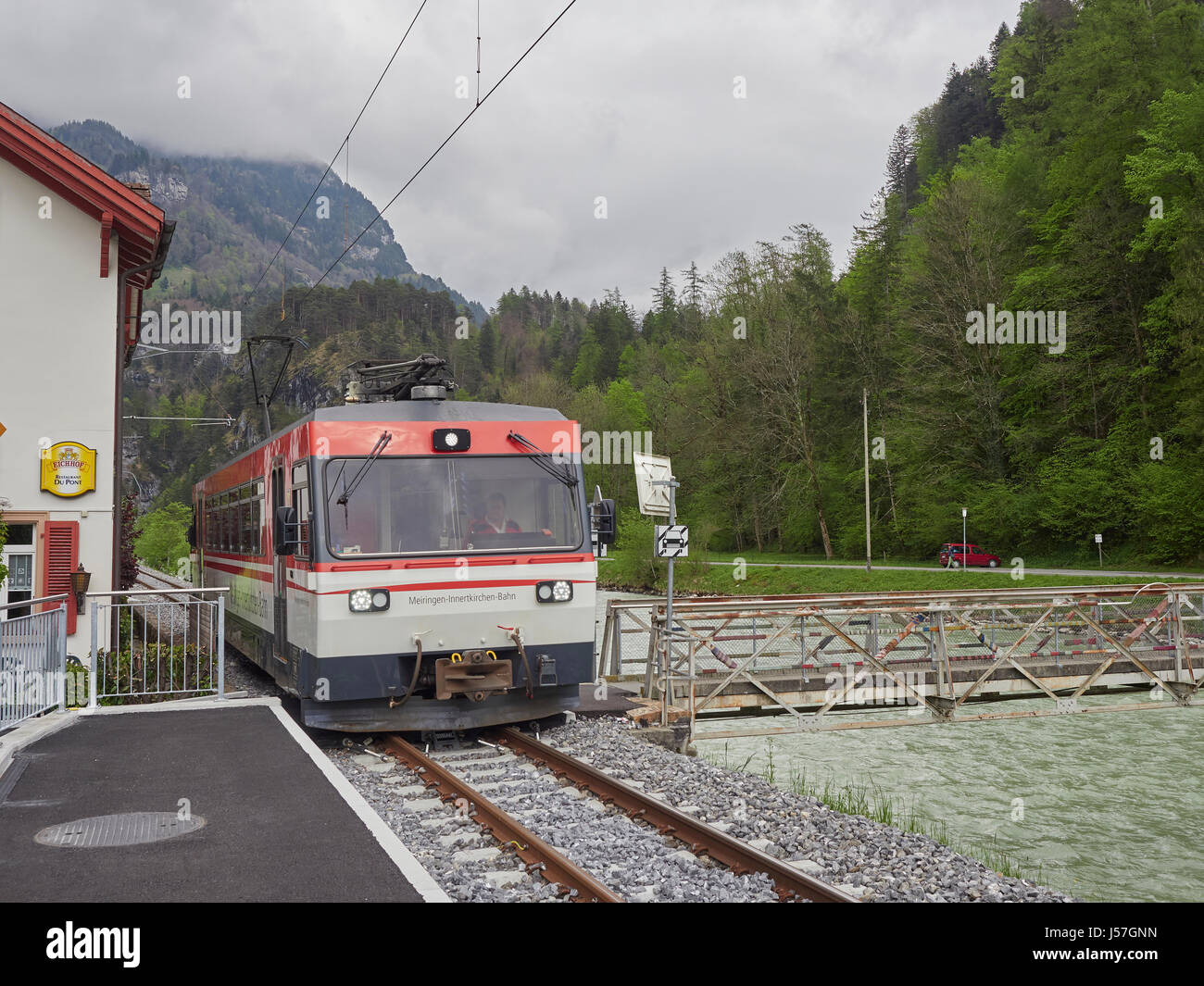 Switzerland the Meiringen–Innertkirchen train at the stop for the Aareschlucht or Aare gorge by the Aare river Stock Photo
