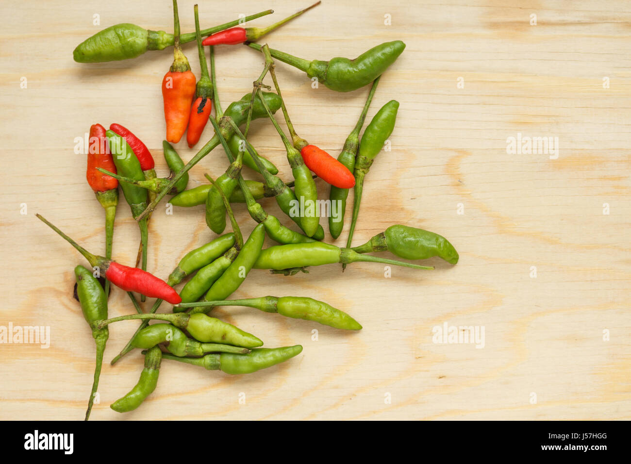Small red and green chilli on wood chopping block Stock Photo - Alamy