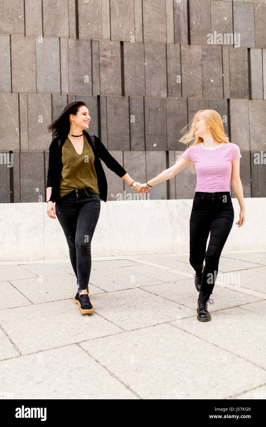 Two young women holding up the hand and walk around. Urban concept ...