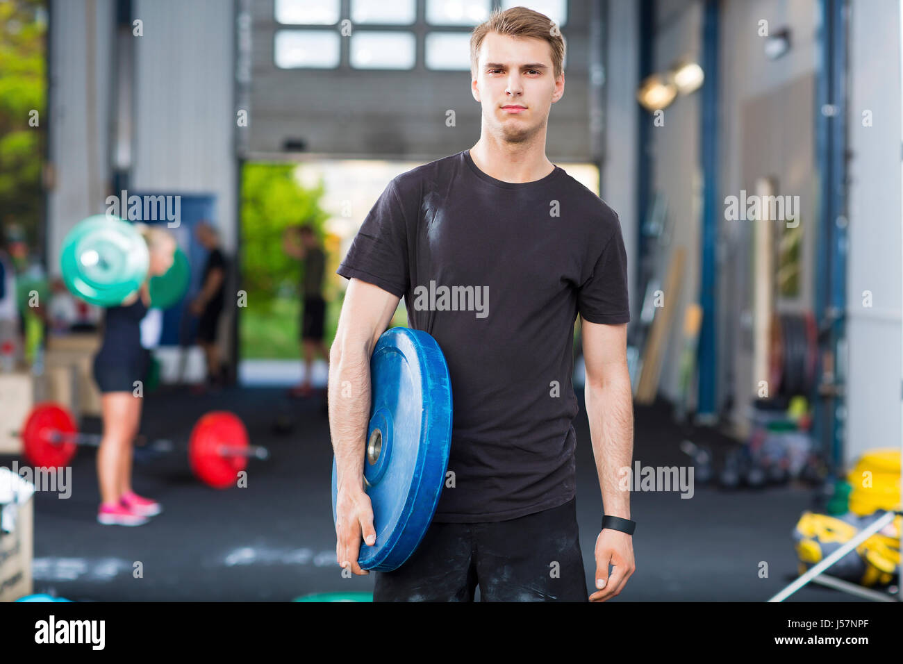 Determined Athlete Carrying Weight Plate In Health Club Stock Photo