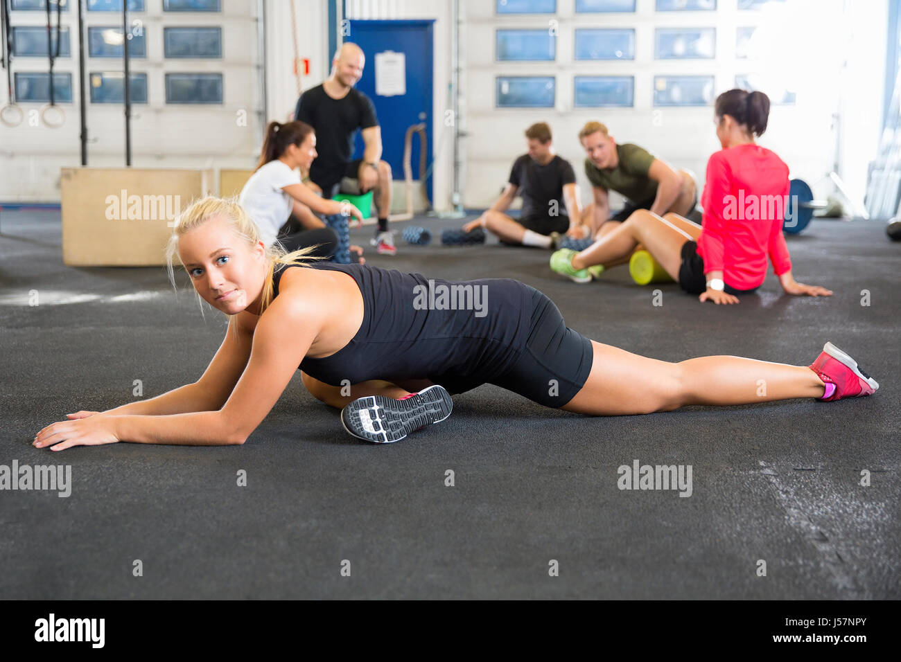 Determined Female Athlete Doing Stretching Exercise At Health Club Stock Photo