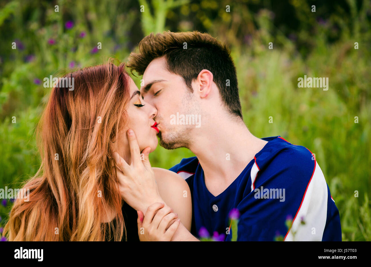 passionate romantic young couple kissing and embracing while in a green park on holiday. Romantic lifestyle and love, outdoors. Stock Photo