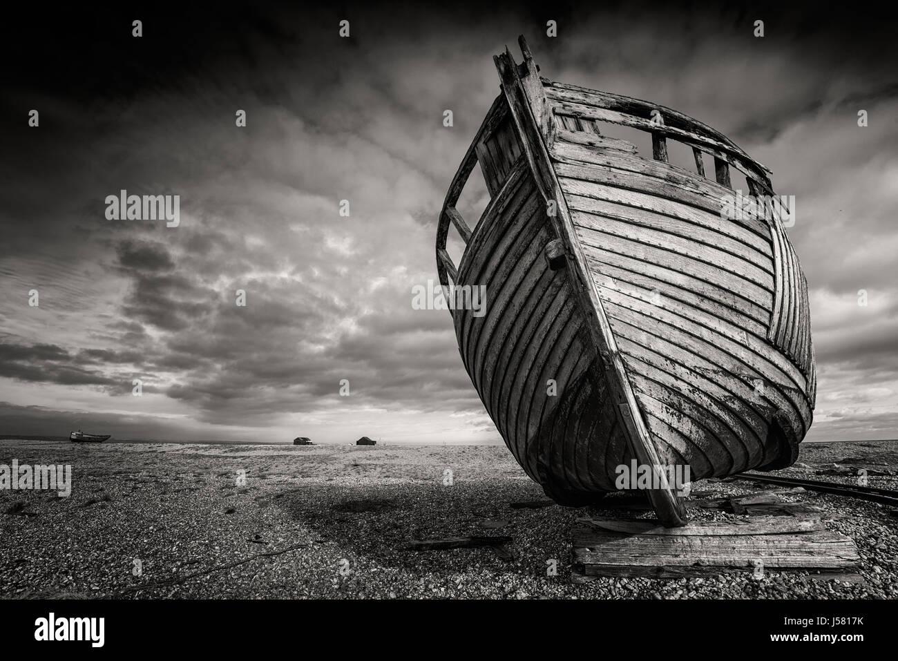 Single abandoned old fishing boat on a pebble beach in monochrome ...