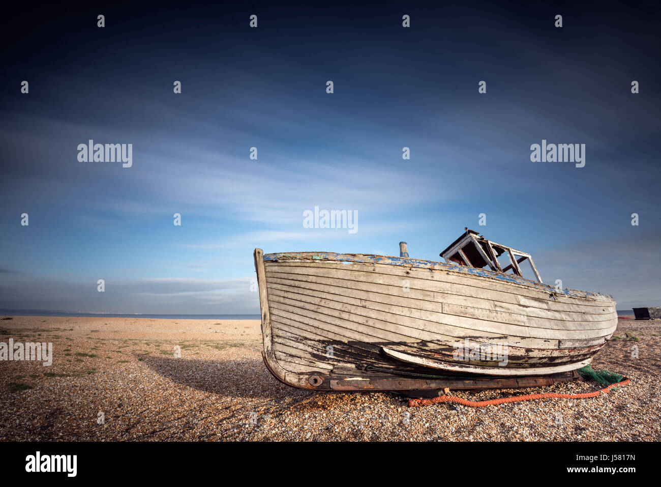 Single abandoned old fishing boat on a pebble beach with long exposure ...