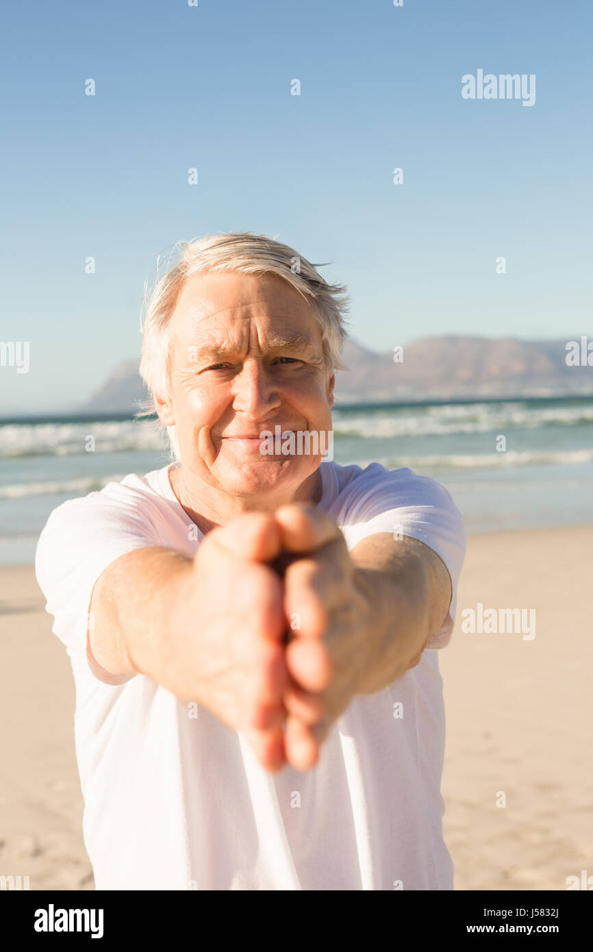Portrait of active senior man practicing yoga at beach Stock Photo