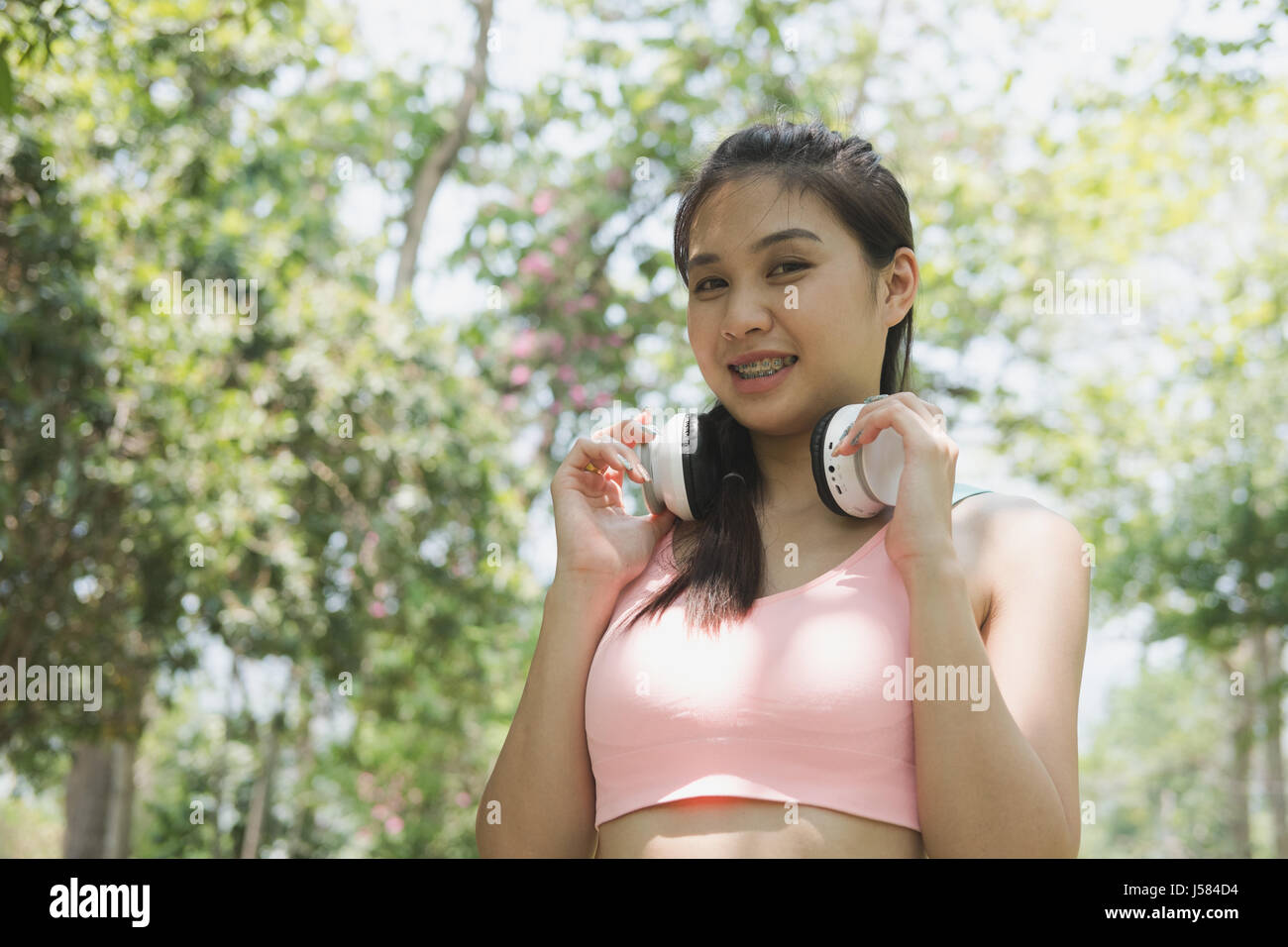 young beautiful asian fitness athlete woman with white headphones preparing for a jogging in summer park. Stock Photo