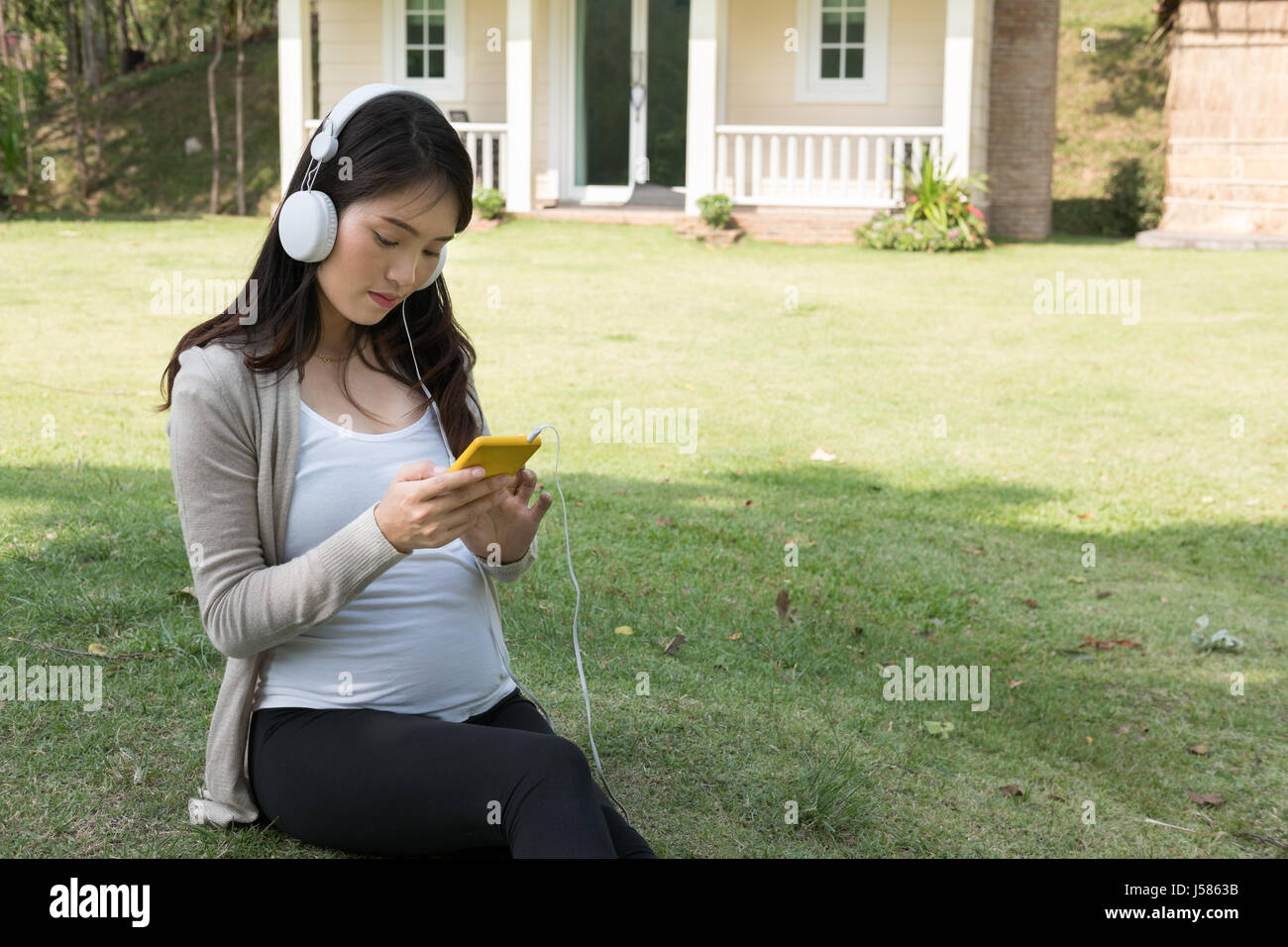 Young asian woman sitting and relaxing on fresh spring grass in garden ...