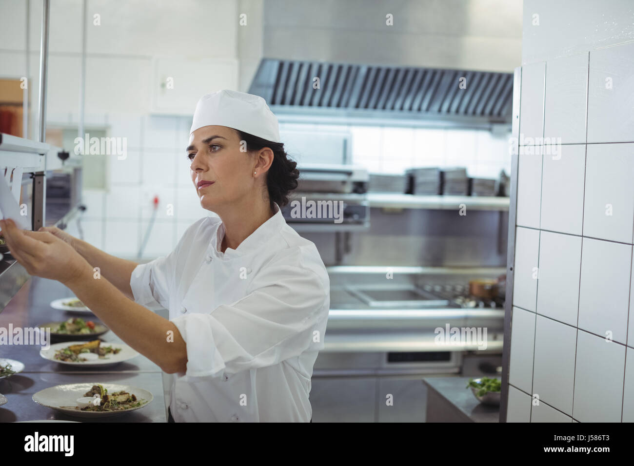 Female Chef Looking At An Order List In The Commercial Kitchen At J586T3 