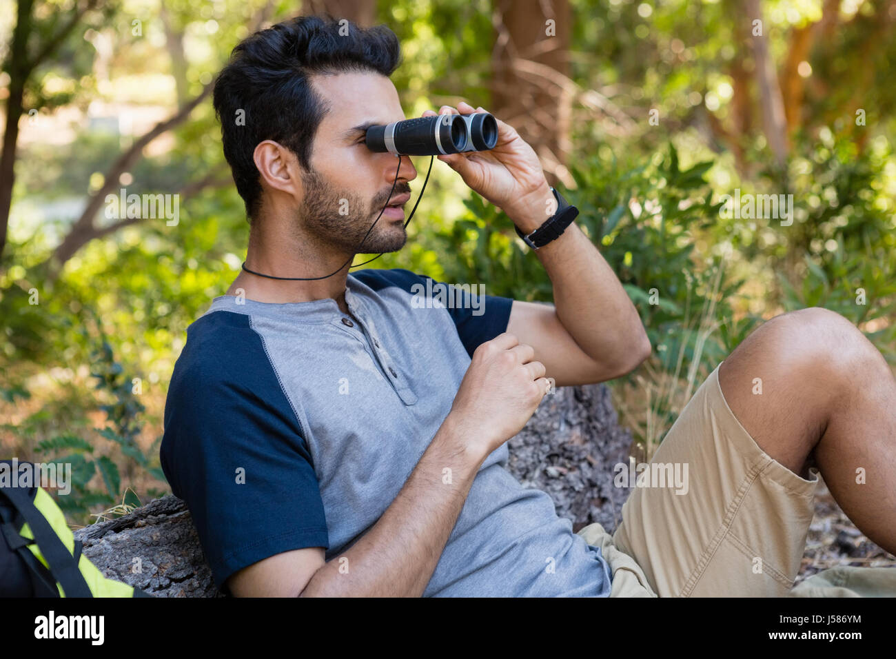 Man looking through binoculars in the forest on a sunny day Stock Photo