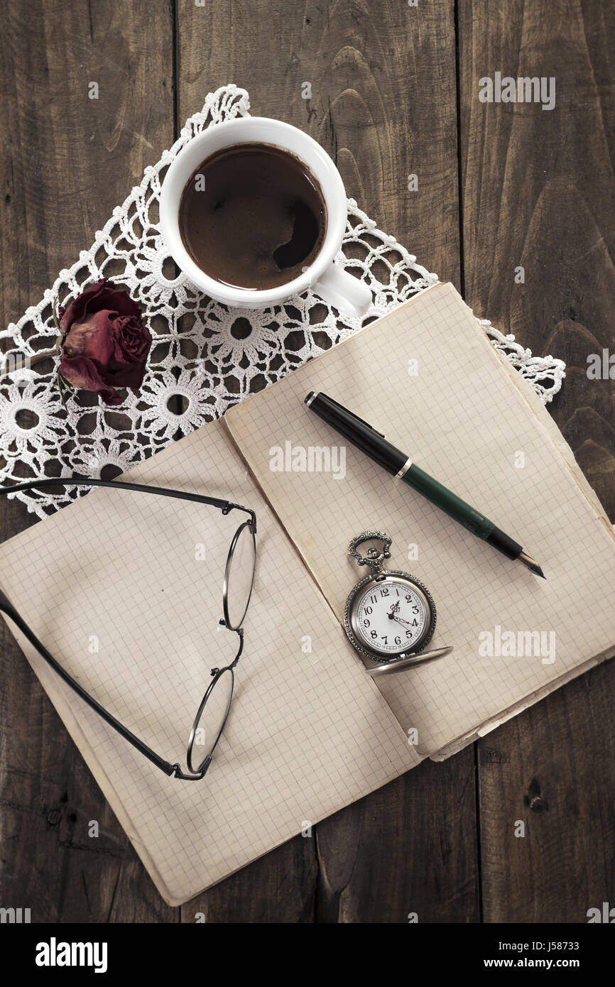 Vintage pocket watch, old book and coffee on wooden table Stock Photo