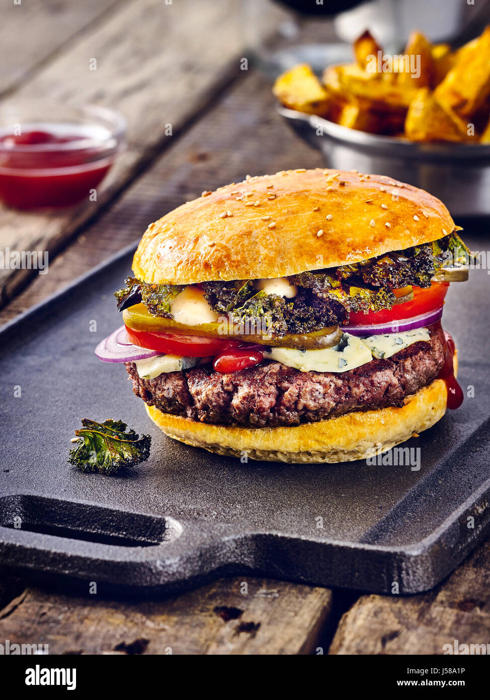 Burger with kale chips and potato wedges Stock Photo