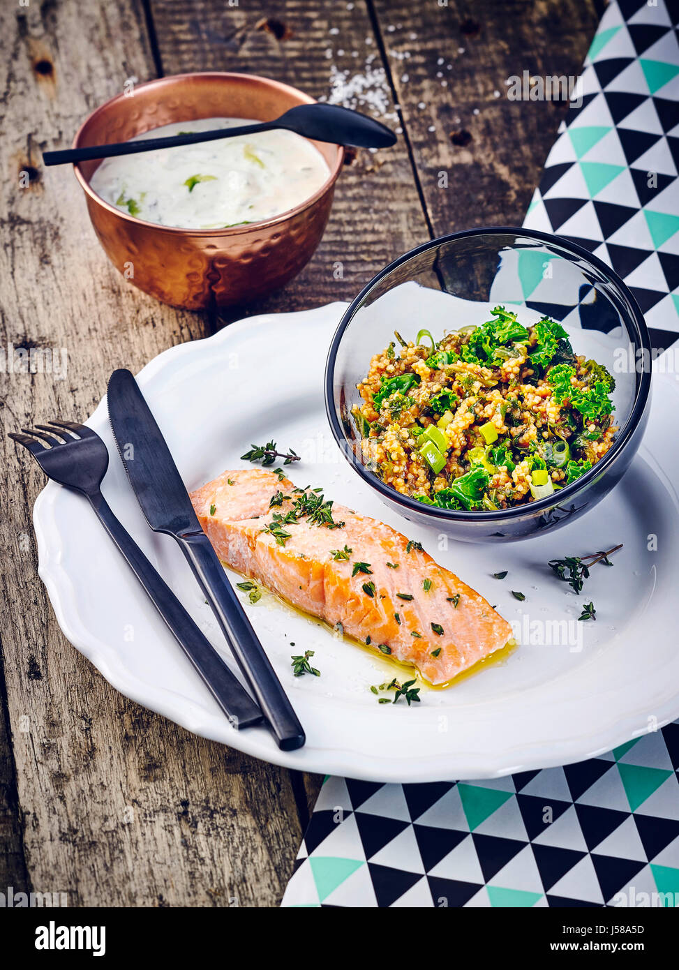 Baked salmon with yoghurt dip and millet salad with kale Stock Photo