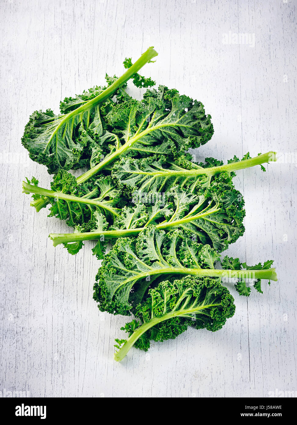 Kale leaves on white wooden surface Stock Photo