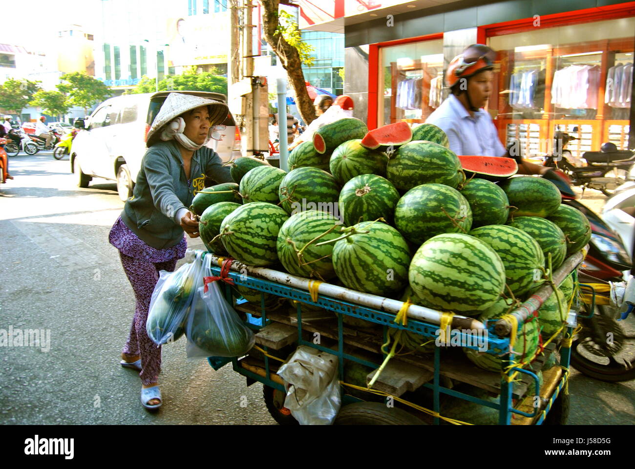 Vietnamese woman pushing melons, Can Tho city, Vietnam Stock Photo