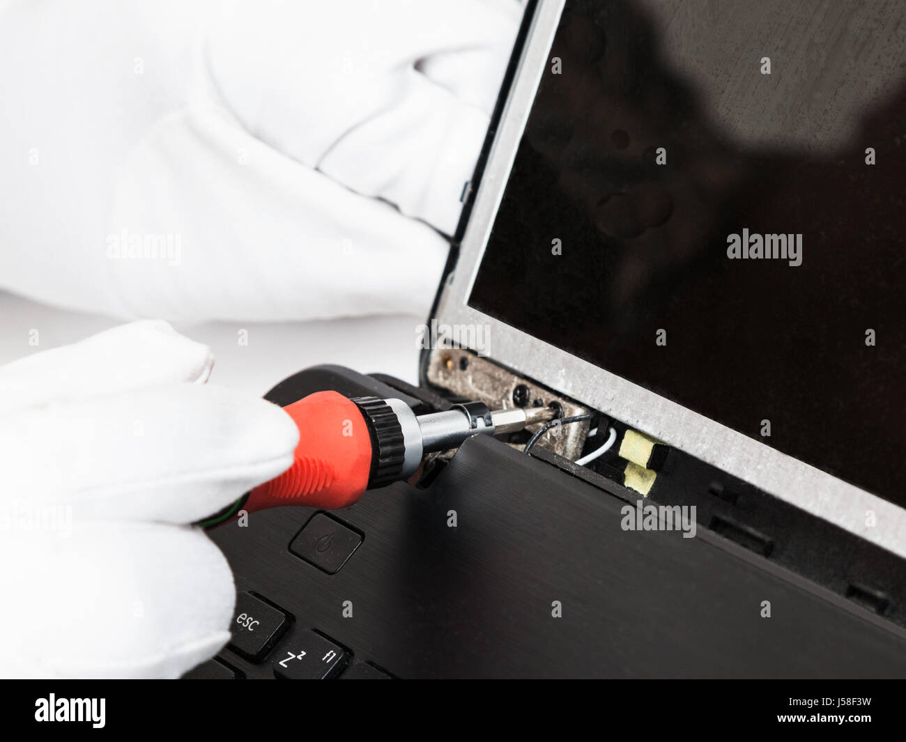 disassembling of laptop serviceman in white gloves fixes LCD screen