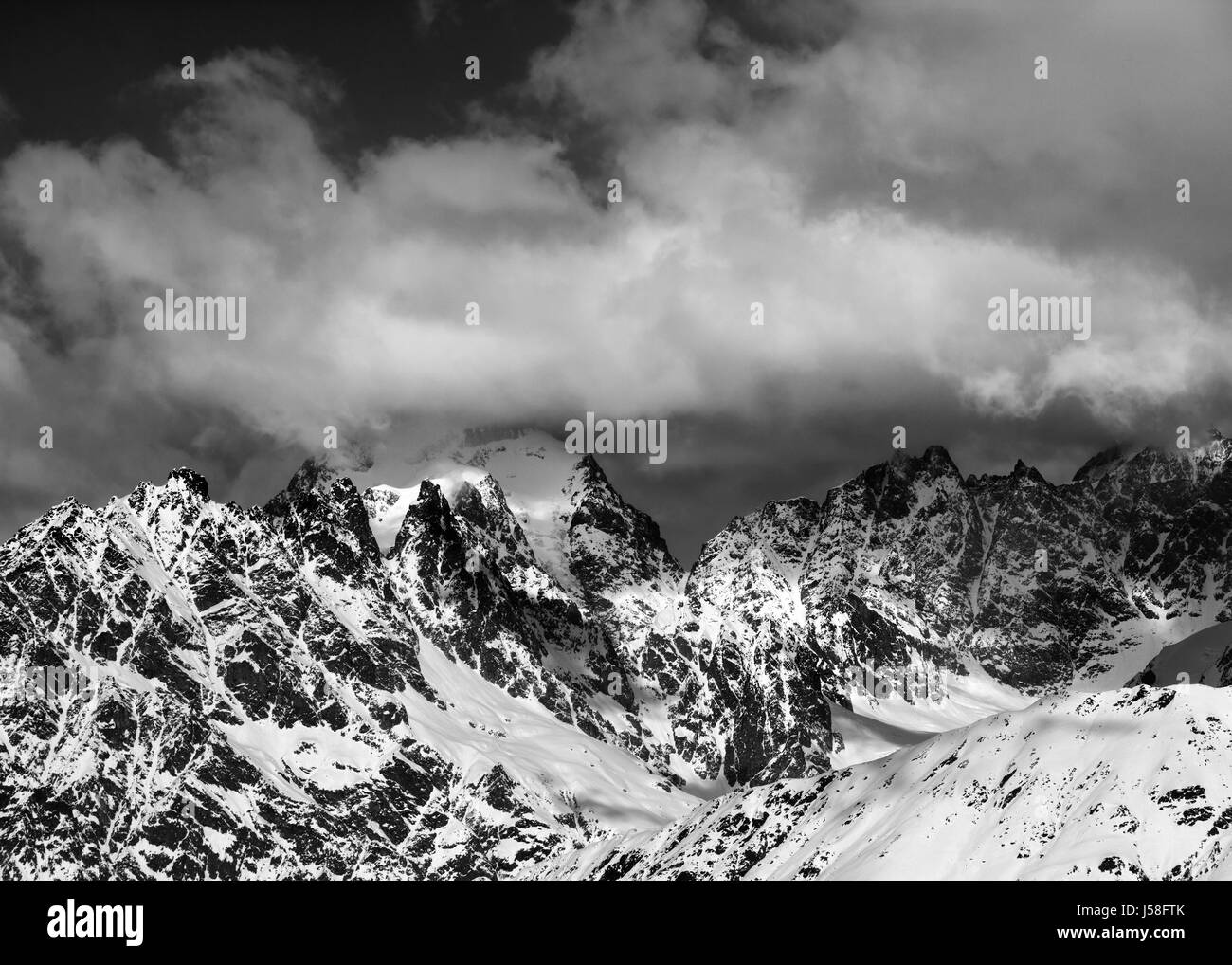 Black and white view on high snowy mountains in clouds at sunny day. Caucasus Mountains. Georgia, region Svaneti. Stock Photo