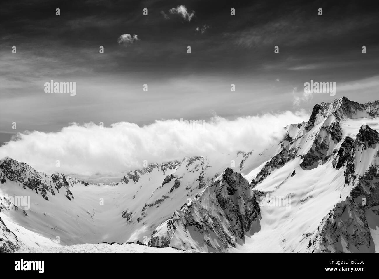 Black and white view on snow sunlight mountains in clouds. Caucasus ...