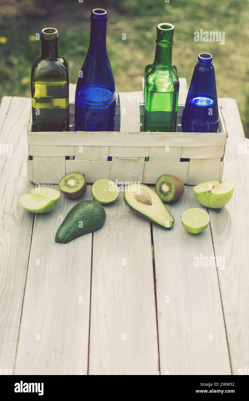 Four bottles of drinks in a white basket and fruits on the white table Stock Photo