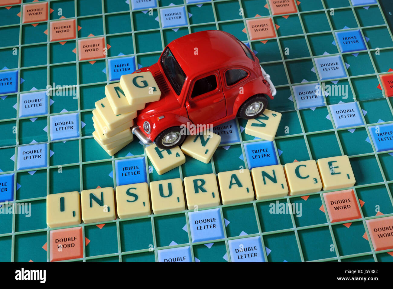 MODEL CAR ON WORD TILE SCRABBLE BOARD SPELLING 'INSURANCE' RE CAR INSURANCE ACCIDENT CLAIMS WHIPLASH MOTOR CRASH BUMP PREMIUMS COSTS COST PRICES UK Stock Photo