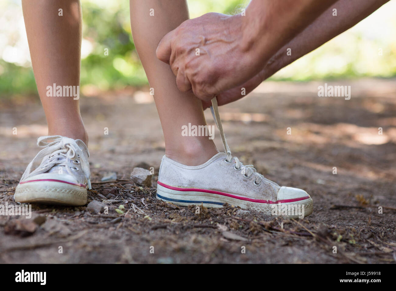 Grandfather tying his granddaughters shoe laces in the forest Stock ...