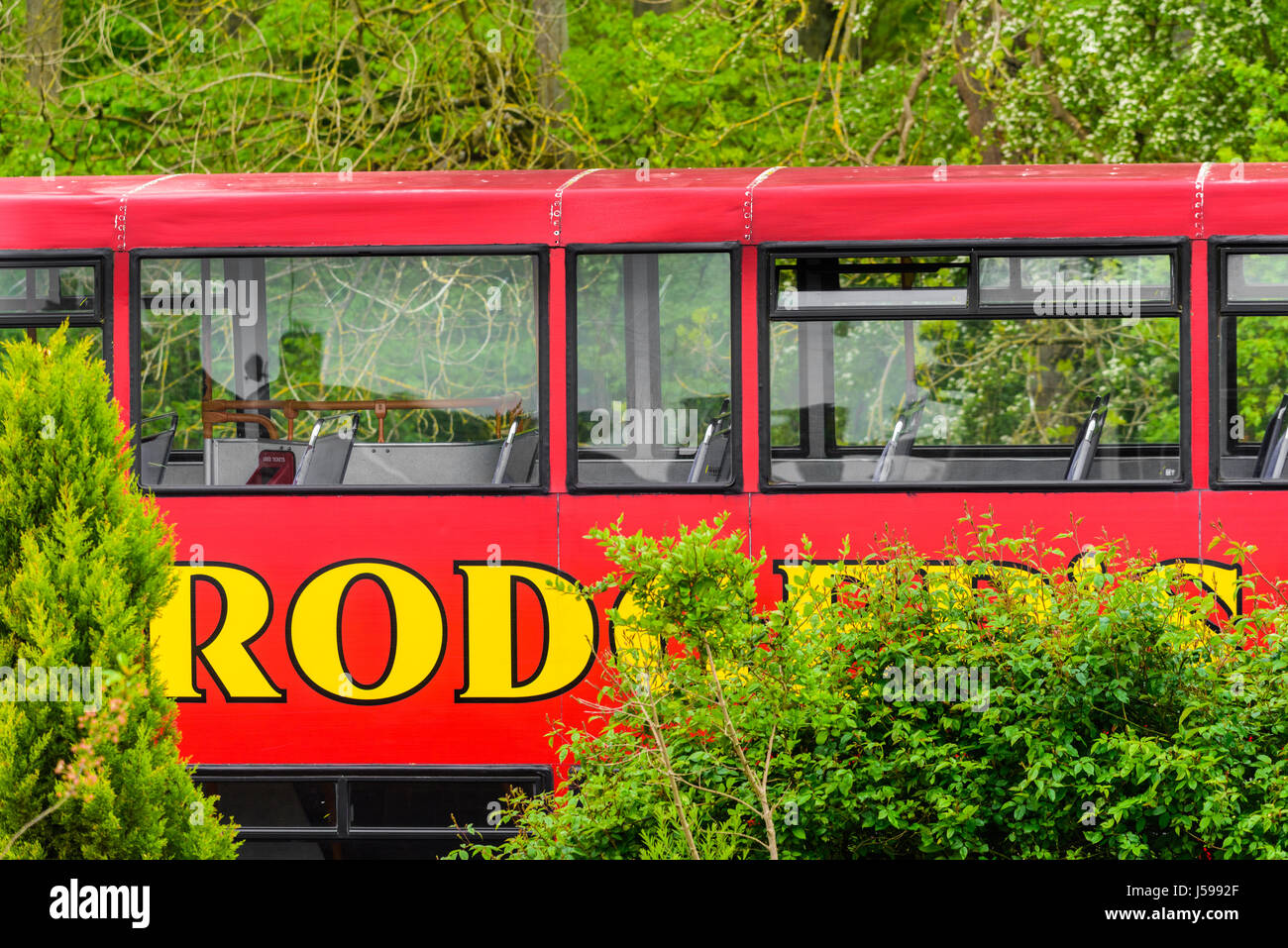 The upper tier of a Rodger's double decker bus in front of a woodland by a street in Corby. Stock Photo