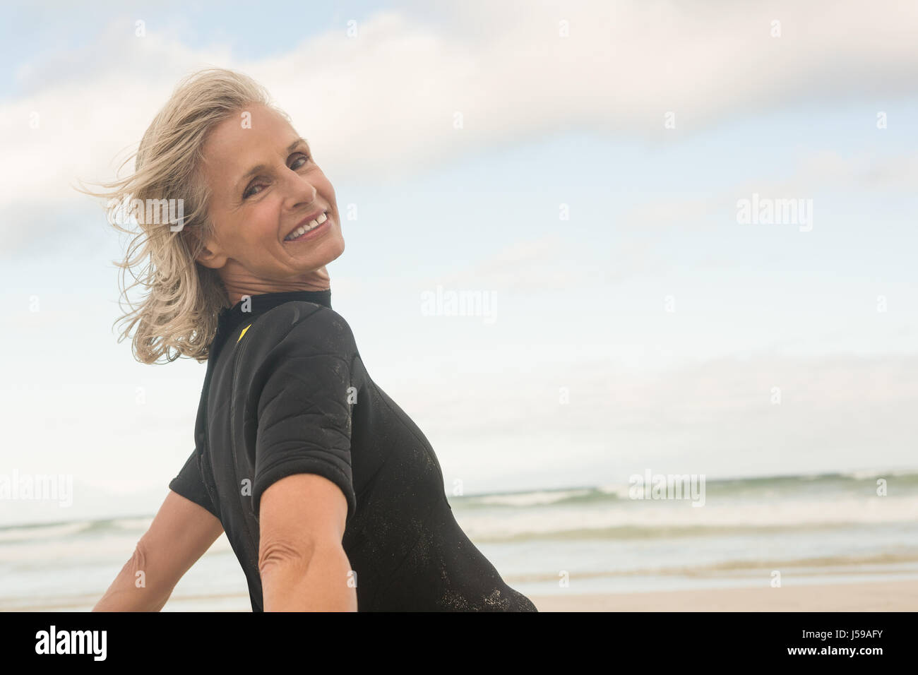 Portrait of smiling woman bending against cloudy sky Stock Photo