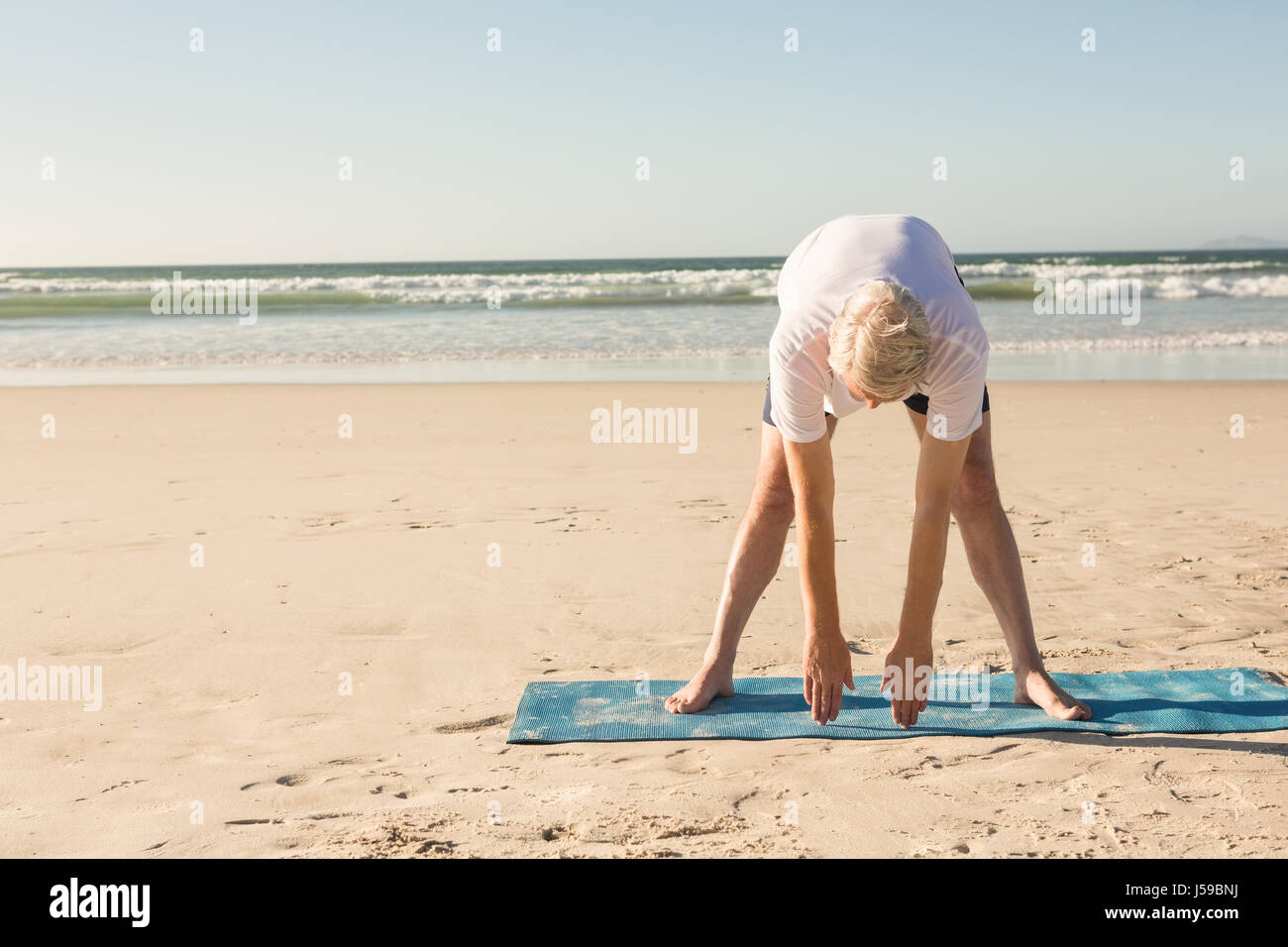 Active senior man exercising at beach Stock Photo