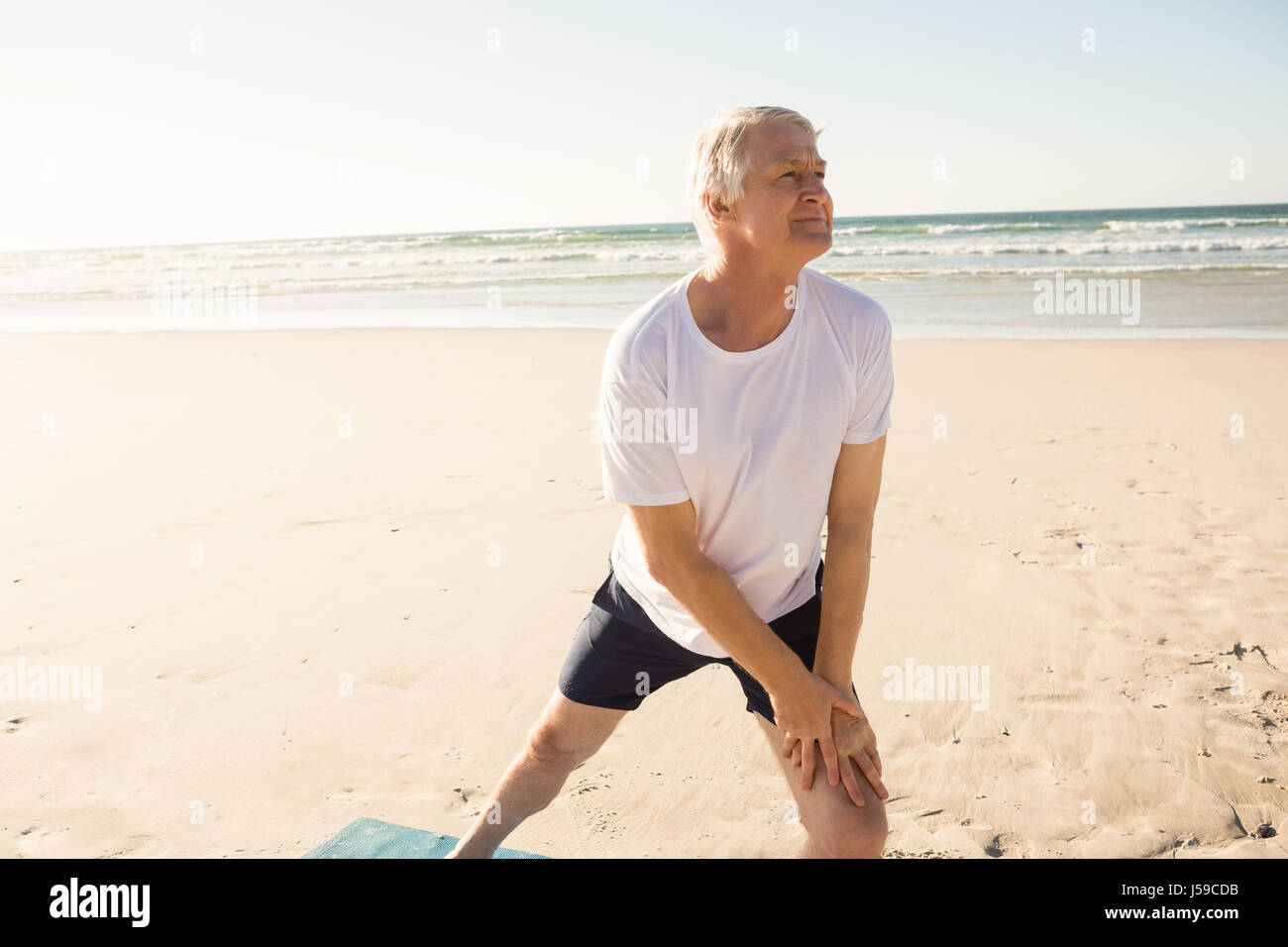 Active senior man stretching at beach Stock Photo