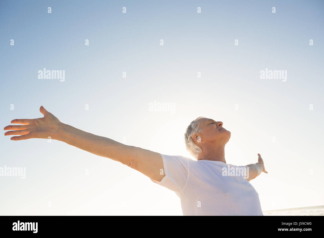Active senior man with arms outstretched standing against clear sky Stock Photo