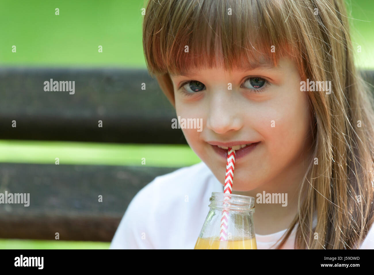 Little girl enjoys a beautiful and sunny day and drinking juice Stock Photo