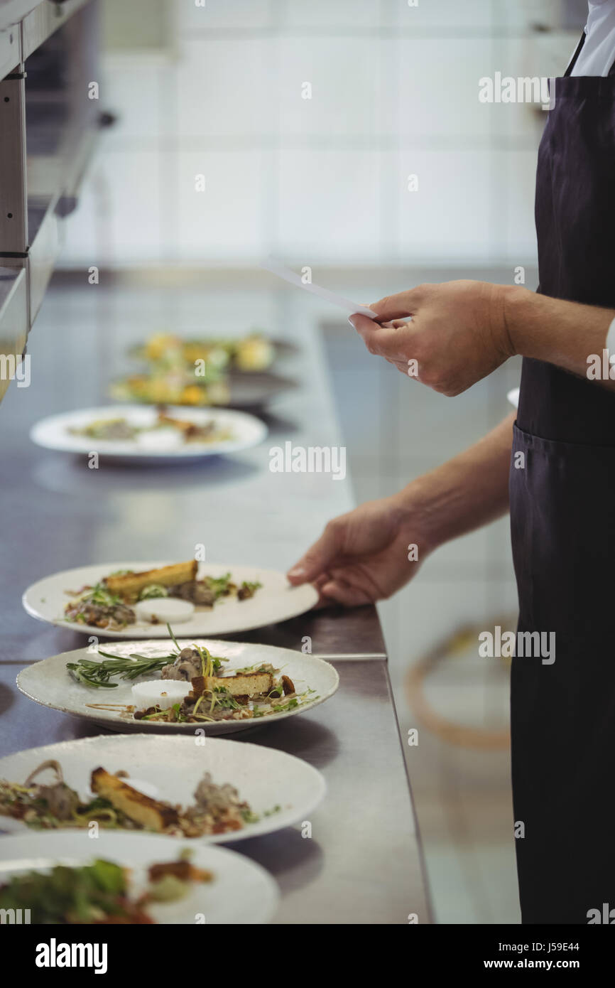 Mid section of chef looking at an order list in the commercial kitchen