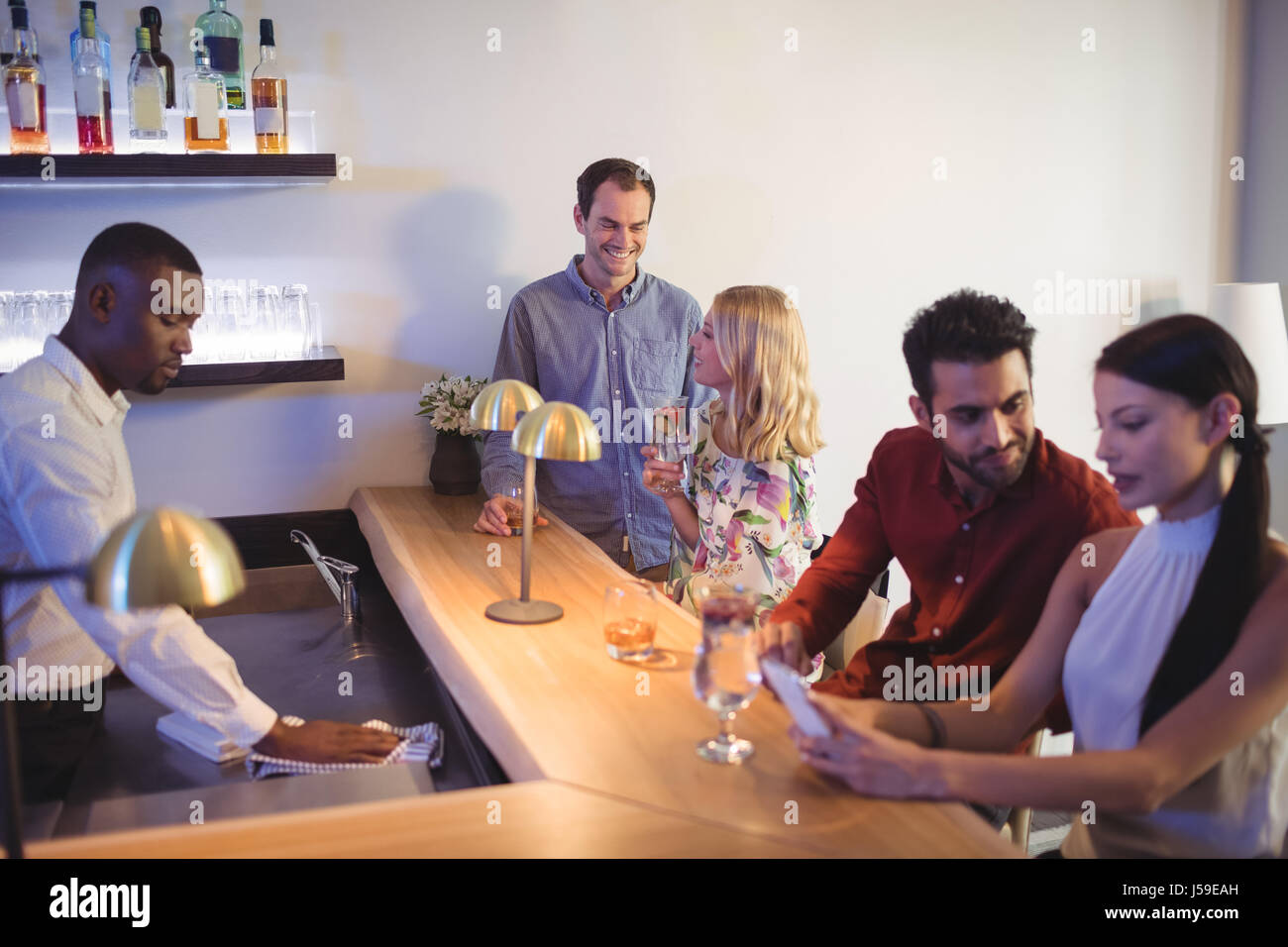 Two couples interacting with each other while sitting at bar counter in